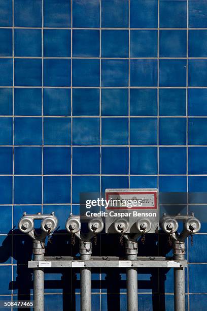 fire hydrants against blue tiled wall - blau kachel stock-fotos und bilder