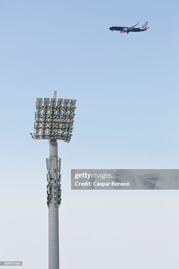 Floodlight and airplane against clear blue sky