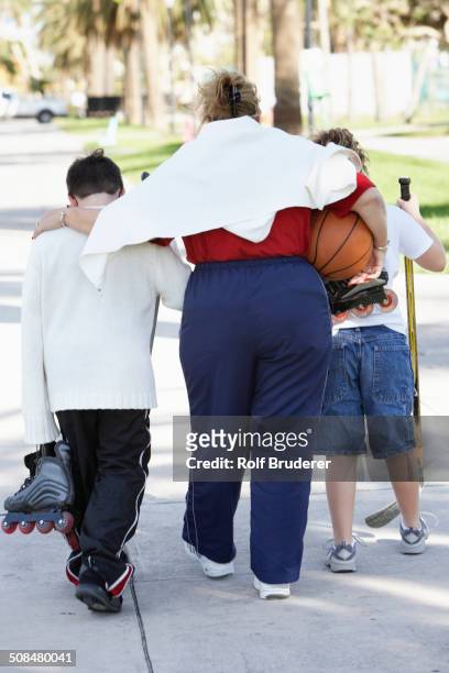 mother and children walking on suburban street - hockey mom stock pictures, royalty-free photos & images
