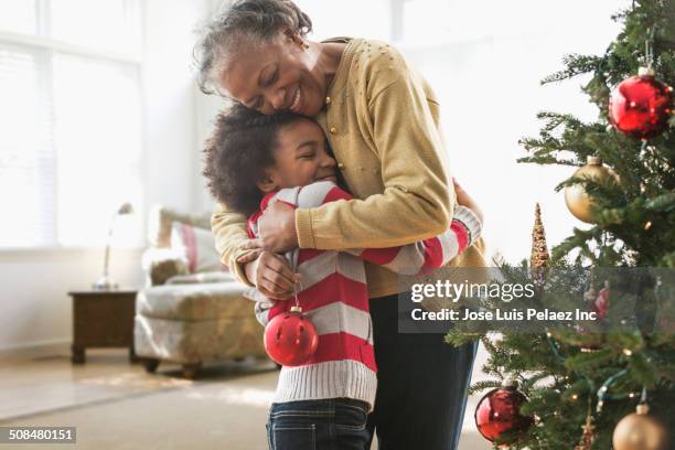 older woman and granddaughter decorating christmas tree - african american christmas images stock-fotos und bilder