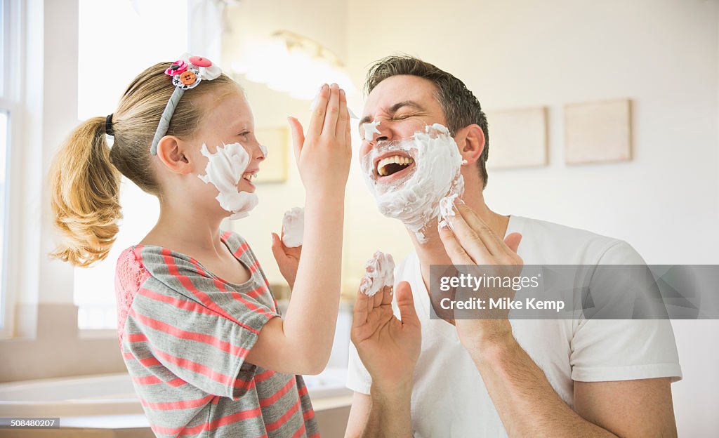 Caucasian father and daughter playing with shaving cream