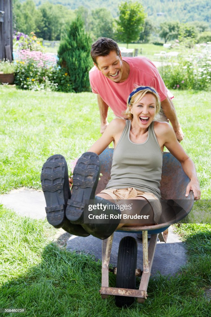Man pushing girlfriend in wheelbarrow