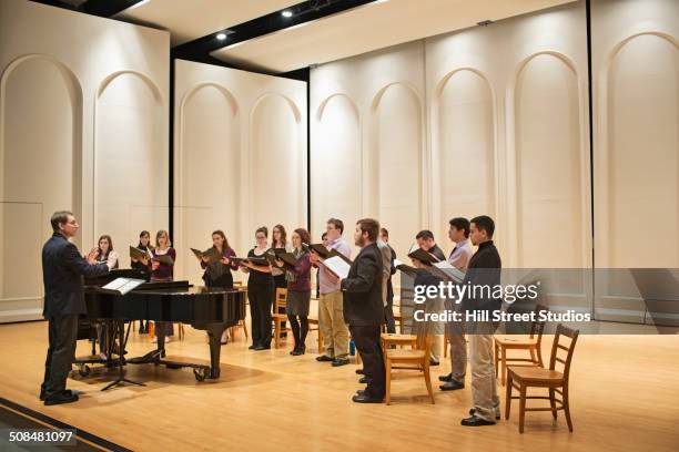 conductor directing choir on stage - choir stage stockfoto's en -beelden