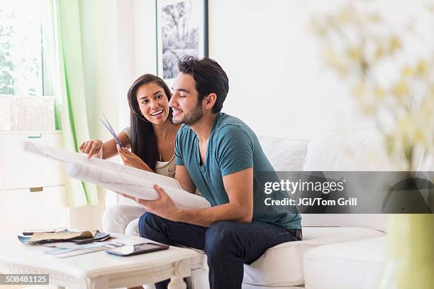 couple examining blueprints in living room - indian living room stock-fotos und bilder