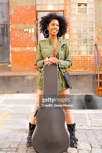 mixed race woman with guitar case on city street - custodia per chitarra foto e immagini stock