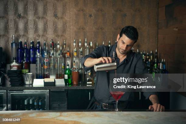 caucasian bartender pouring drinks at bar - bartender foto e immagini stock