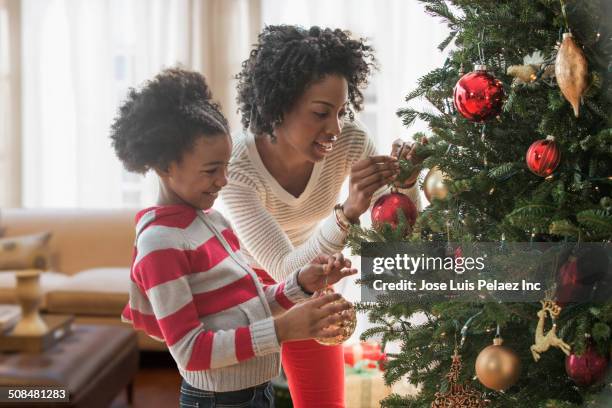 mother and daughter decorating christmas tree - kerstboom versieren stockfoto's en -beelden