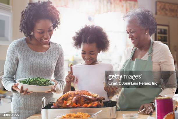 three generations of women cooking together in kitchen - black mother and child cooking stock-fotos und bilder