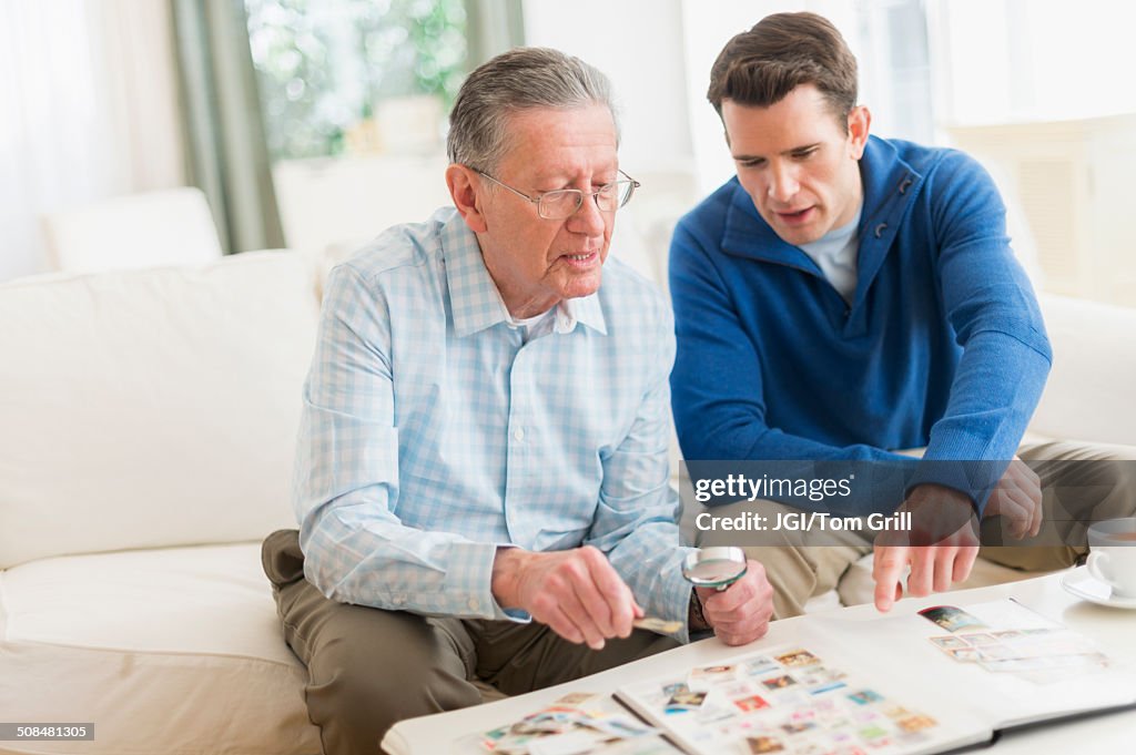 Caucasian father and son examining stamp collection