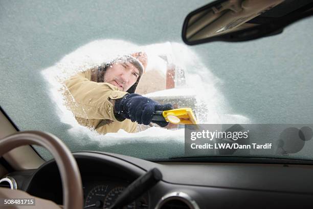 caucasian man scraping snow off car windshield - winter car window stock-fotos und bilder