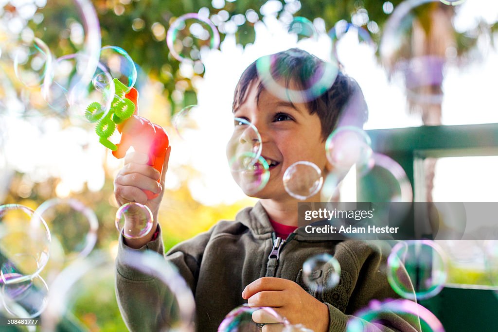 Mixed race boy playing with bubbles outdoors