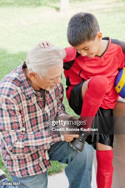 older hispanic man tying grandson's shoelaces - boy tying shoes stock-fotos und bilder