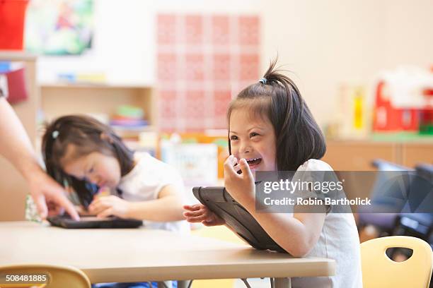 Mixed race Down syndrome student using tablet computer in classroom