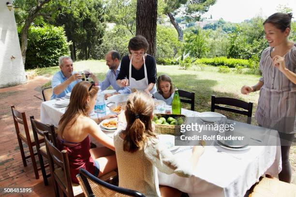 family eating together at table outdoors - italien familie stock-fotos und bilder