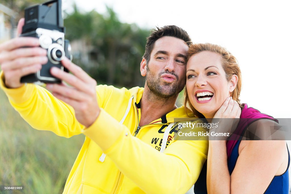 Caucasian couple taking self-portrait with vintage camera