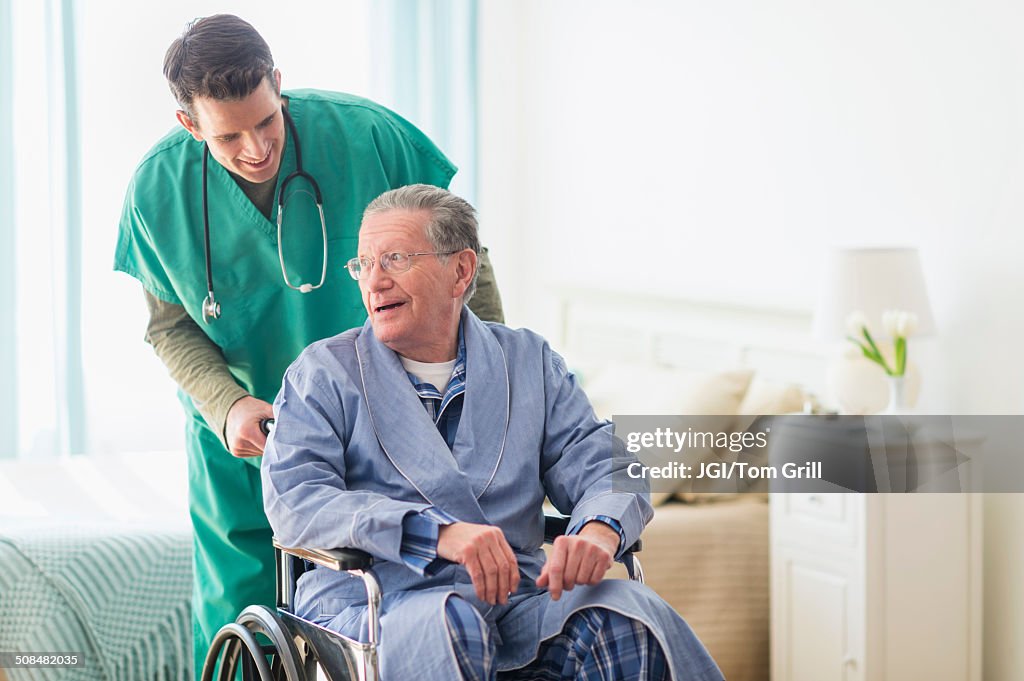 Caucasian nurse wheeling patient in home