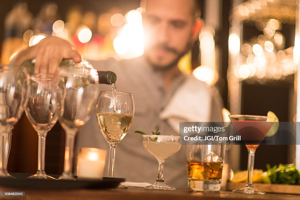 Hispanic bartender pouring drinks at bar