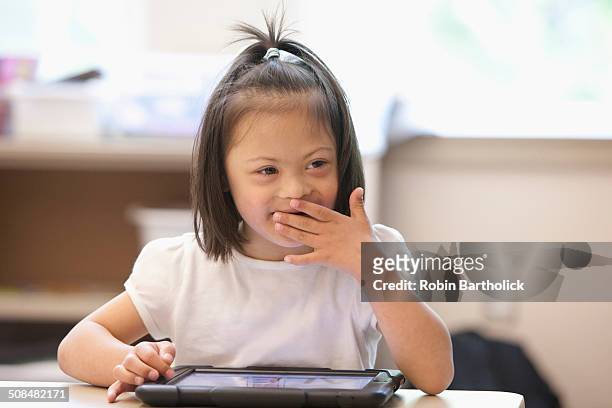 Mixed race Down syndrome student using tablet computer in classroom
