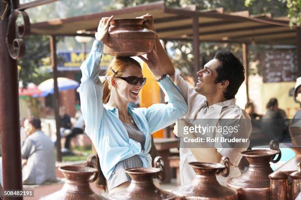 couple admiring pottery at outdoor market - bazaar market stock-fotos und bilder