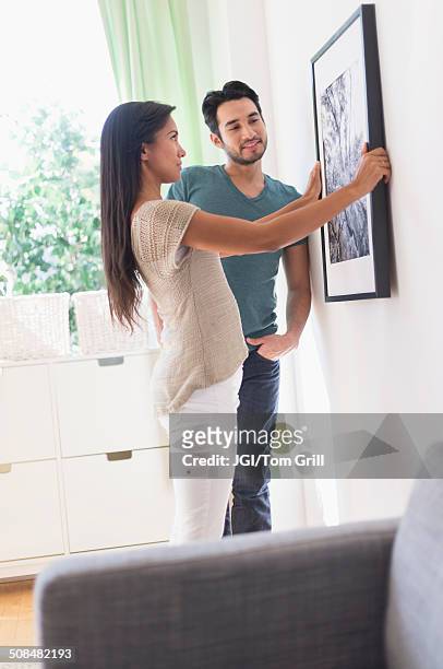 couple hanging picture together - house for an art lover stock pictures, royalty-free photos & images