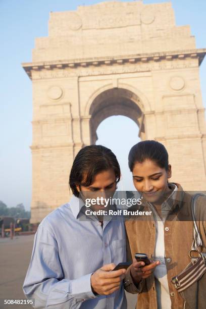 indian couple using cell phone by india gate, delhi, india - india gate stock pictures, royalty-free photos & images