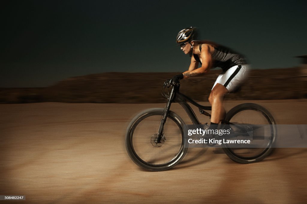 Woman riding mountain bike in desert