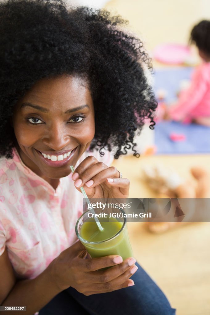 Smiling woman drinking green juice