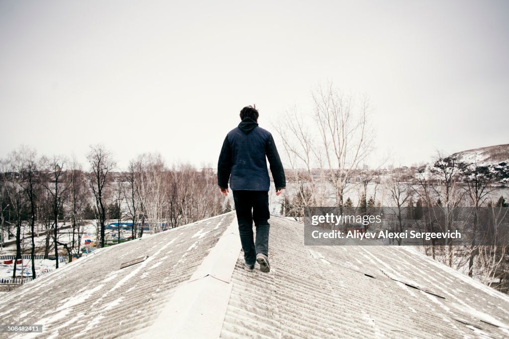 Caucasian man walking on snowy roof