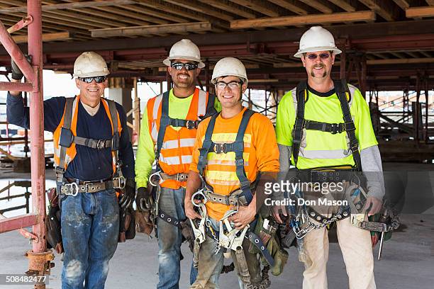 workers smiling at construction site - sicherheitsausrüstung stock-fotos und bilder