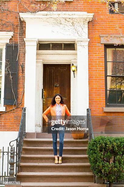 mixed race woman smiling on front stoop - portico sopraelevato foto e immagini stock