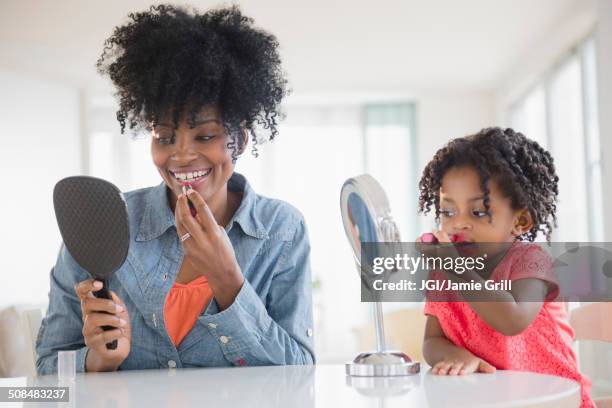 mother and daughter applying makeup - erwachsene imitieren stock-fotos und bilder