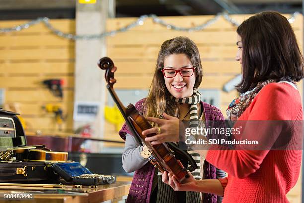 woman having violin repaired in music store - music shop stock pictures, royalty-free photos & images