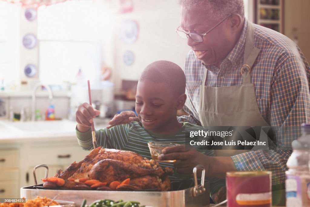 Older man and grandson cooking together in kitchen