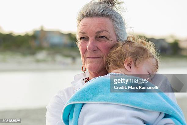 caucasian woman carrying grandson on beach - grandma sleeping stock pictures, royalty-free photos & images