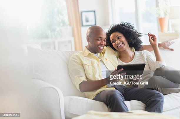 couple using digital tablet together - couple with ipad in home stock pictures, royalty-free photos & images