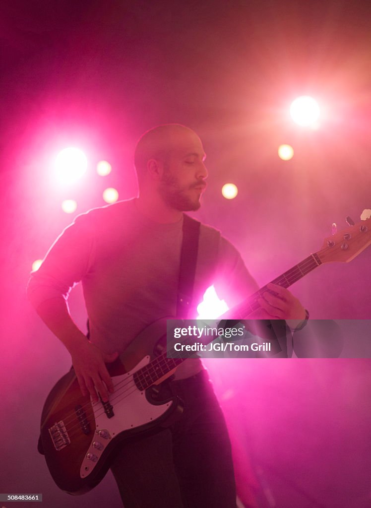 Hispanic musician playing electric guitar on stage