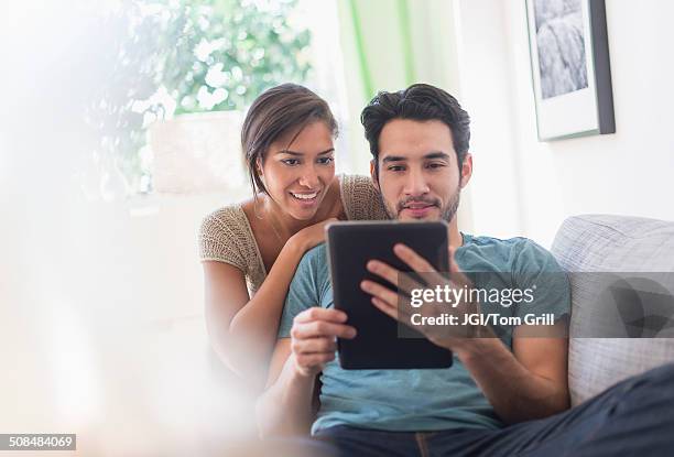 couple using digital tablet together - mixed race person stock photos et images de collection