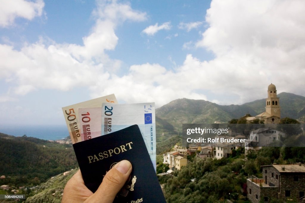 Passport and Euros overlooking rural landscape, Italy, Linguria, Italy
