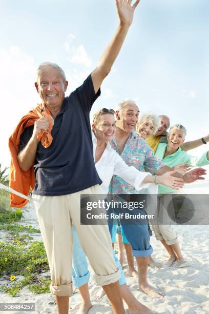 senior friends waving on beach - active seniors florida stock pictures, royalty-free photos & images