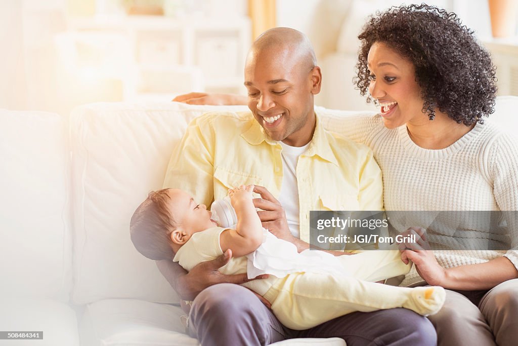 Parents feeding baby on sofa