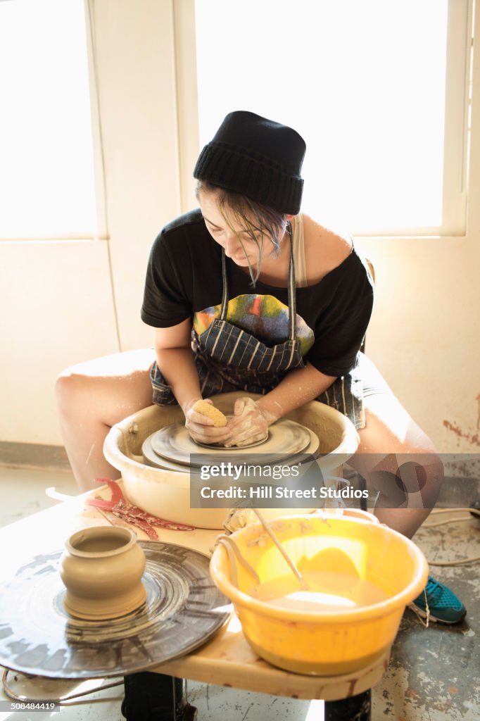 Mixed race student throwing pottery on wheel