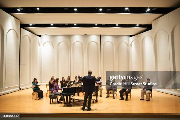 conductor directing choir on stage - act score stock-fotos und bilder