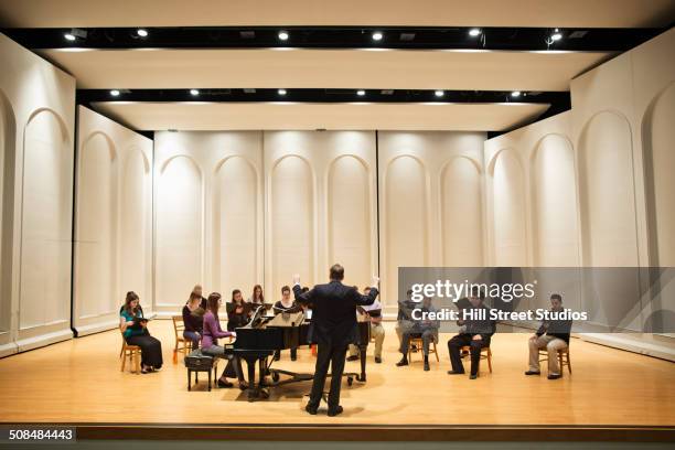 conductor directing choir on stage - sala de concertos - fotografias e filmes do acervo