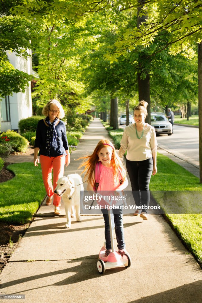 Caucasian family walking dog on suburban sidewalk