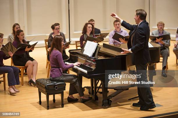 conductor directing choir on stage - choir stage stock pictures, royalty-free photos & images