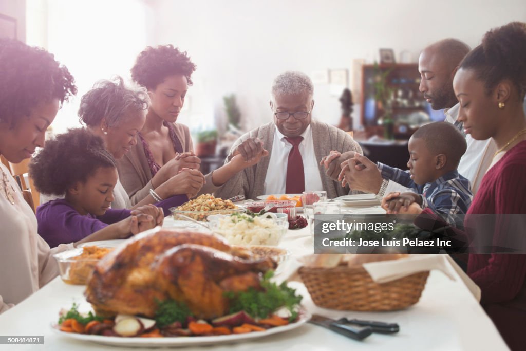 Family saying grace at holiday table