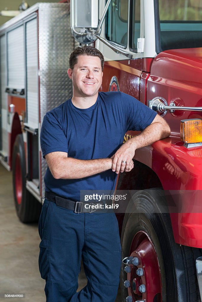 Firefighter leaning against fire rescue truck at station