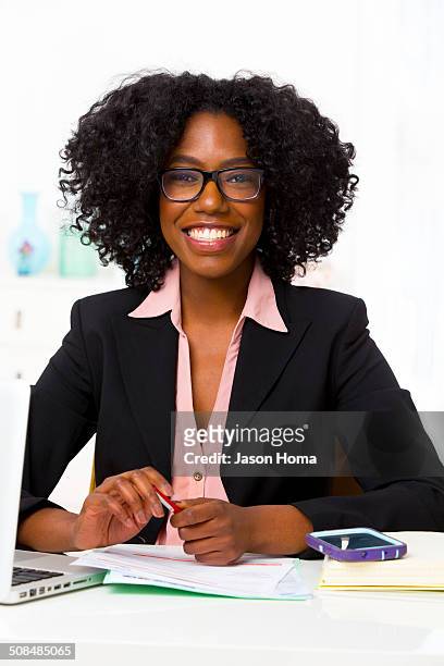 mixed race businesswoman smiling at desk - afro caribbean and american stock-fotos und bilder