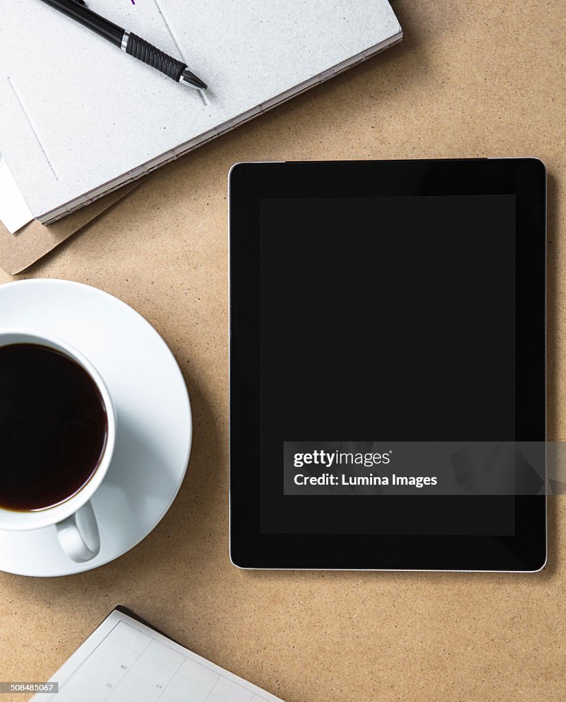 Tablet computer on table with book and coffee