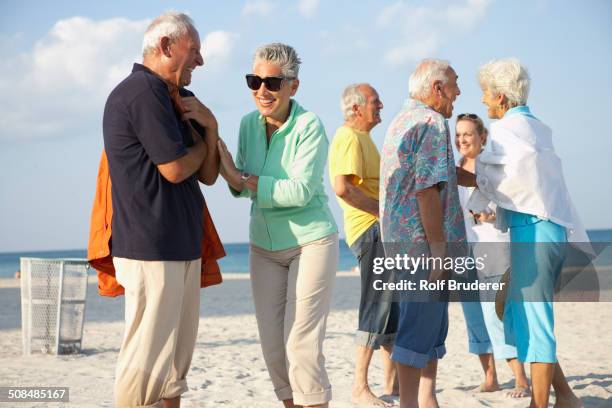 senior friends talking on beach - celebration fl stock pictures, royalty-free photos & images